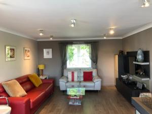 a living room with a red couch and a window at 9 The Coach House in Rye in Rye