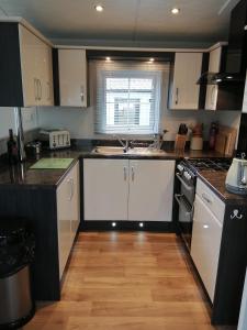 a kitchen with white cabinets and a wooden floor at No1 Borwick Lakes in Carnforth