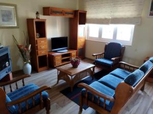 ein Wohnzimmer mit blauen Stühlen und einem TV in der Unterkunft A Pedriña Ribadeo in Ribadeo
