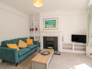 a living room with a green couch and a fireplace at Bluebell Apartment in Swanage