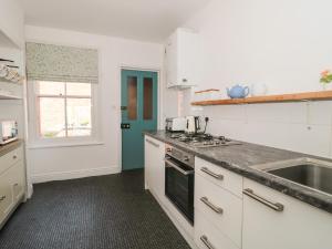 a kitchen with white cabinets and a sink and a window at Bluebell Apartment in Swanage
