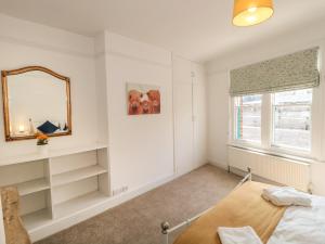una camera da letto con specchio, letto e finestra di Bluebell Apartment a Swanage