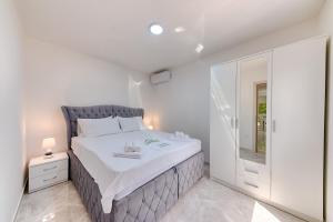 a white bedroom with a large bed and a window at Apartmani Panorama in Bar +18 photos