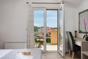 a bedroom with a bed and a desk and a balcony at B&B Villa Oasa 1 in Rovinj