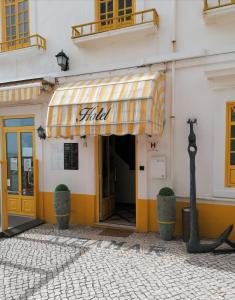 un edificio giallo e bianco con un tendone sopra di Hotel Ribamar a Nazaré