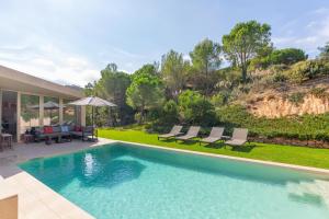 a swimming pool with chairs and a house at Villa Alba in Santa Cristina d'Aro