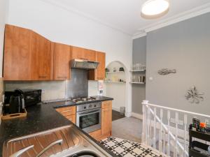 a kitchen with wooden cabinets and a stove top oven at Rothlea Flat 1 in Pwllheli