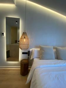 a bedroom with a white bed and a mirror at S´Estancia Suites in Es Mercadal