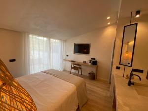 a bedroom with a bed and a desk and a television at S´Estancia Suites in Es Mercadal