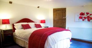 a bedroom with a bed with a red blanket on it at Colston Hall Farmhouse B&B in Framlingham