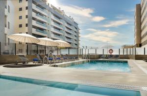 a swimming pool with chairs and umbrellas and a building at Gran Hotel Luna de Granada in Granada