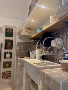 une cuisine avec un comptoir et des étagères avec de la vaisselle dans l'établissement Grezze Mura, à Fasano