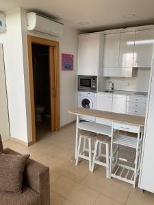 kuchnia z białymi szafkami oraz stołem i stołkiem w obiekcie Loft luminoso Alcorcón M-40 Madrid w mieście Alcorcón
