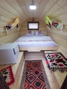 a bedroom in a log cabin with a bed and a rug at Cabana Ocna Mesaros in Ocna Şugatag