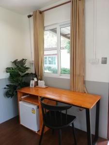 uma secretária num quarto com uma janela e uma cadeira em Sameikei Homestay em Phrae