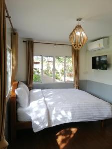 a bedroom with a white bed and a window at Sameikei Homestay in Phrae