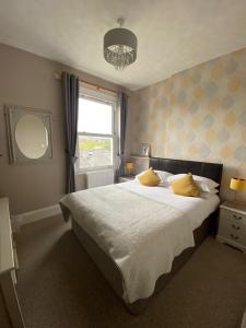 a bedroom with a large bed with yellow pillows at Buckingham Lodge Guest House in Torquay