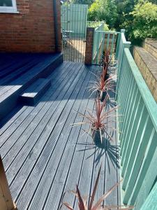 a wooden deck with two potted plants and a fence at Stratford Upon Avon Pearl in Stratford-upon-Avon