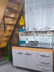 une cuisine avec un évier et un escalier en bois dans l'établissement Tiny House moçambique - Sua casinha em Floripa!, à Florianópolis