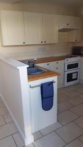 a kitchen with white cabinets and a sink at The Annex in Skegness