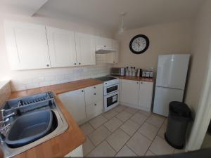 a kitchen with white cabinets and a clock on the wall at The Annex in Skegness