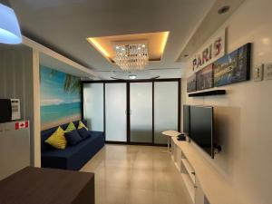 a living room with a blue couch and a tv at Honey's Elysees Condotel - Davao in Davao City