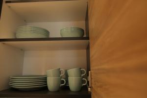 un armario con platos y tazas en un estante en Bonanza Apartments en Niš