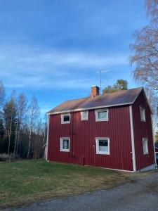 a red barn with a red roof on a field at Summer in the North of Sweden in Bjurholm