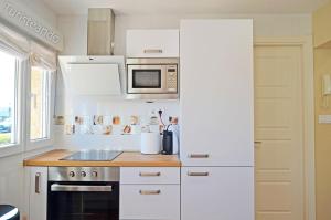 a kitchen with white cabinets and a microwave at Apartamento Marejada - Para amantes de la luz y las casas acogedoras in San Vicente de la Barquera