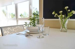 Biały stół z dwoma kieliszkami, miską i kwiatami w obiekcie Apartamento Marejada - Para amantes de la luz y las casas acogedoras w mieście San Vicente de la Barquera +23 zdjęcia