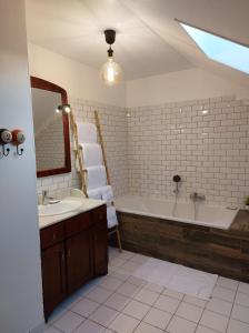 uma casa de banho com uma banheira, um lavatório e um espelho. em La Belle Vue Gîte Champenois B&B em Bergères-lès-Vertus