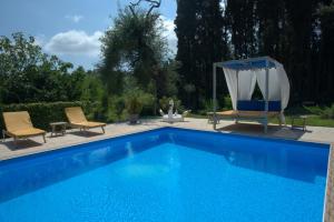 a blue swimming pool with two chairs and a gazebo at Ilias Apartments in Ýpsos