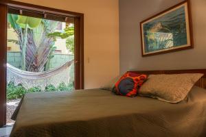 a bedroom with a bed with a large window at Casa Viva Itamambuca in Ubatuba