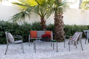 a patio with two chairs and a table and a palm tree at MrBrown - Cinzia Resort Beach in Mazara del Vallo