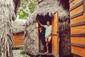 un homme debout à l'entrée d'une maison au toit de chaume dans l'établissement Raiz Kite Cabana, à Jericoacoara