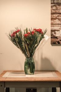 a vase filled with red roses sitting on a table at Bv Apartments Conditioning House Bradford in Bradford