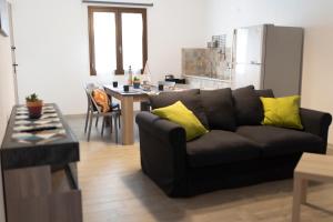 a living room with a black couch and a kitchen at MrBrown - Cinzia Resort Beach in Mazara del Vallo