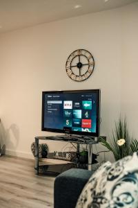 a flat screen tv sitting in a living room with a clock at Bv Apartments Conditioning House Bradford in Bradford