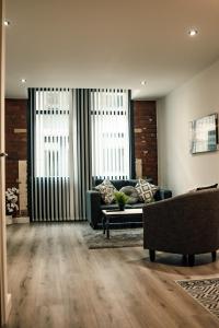 a living room with a couch and two windows at Bv Apartments Conditioning House Bradford in Bradford