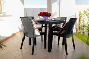 a dining room table with four chairs and flowers on it at MrBrown - Cinzia Resort Beach in Mazara del Vallo