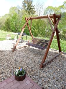a swing set with a flower pot and a bench at Domek nad Potokiem in Szczytna