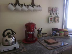 B&B Vaiana في Maida: طاولة مطبخ مع آلة صنع القهوة وأكواب على الحائط