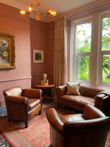 a living room with a couch and chairs and windows at Mary's Court Guest House - Mairlys in Betws-y-coed