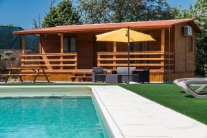 Cabaña de madera con piscina y sombrilla en Encosta do Sonho en Vieira do Minho