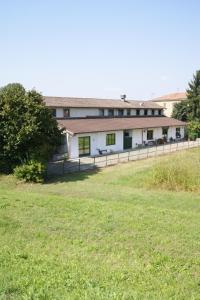 a white building with a fence in a field at Agriturismo La Valbona in San Martino Siccomario