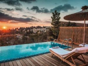 a swimming pool on a deck with an umbrella at Gordonia Private Hotel in Ma'ale HaHamisha