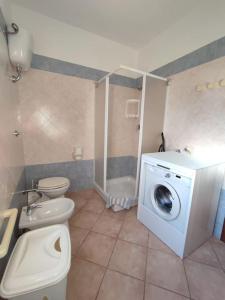 a bathroom with a toilet and a washing machine at Casa Paguro, la Tua casa in Sardegna in Porto San Paolo