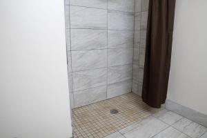 a bathroom with a shower with a tiled floor at BlissPoint Inn & Suites Marion in Marion +32 photos