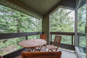 - une table et des chaises sur une terrasse couverte dotée de fenêtres dans l'établissement Powderview 24 by Outpost Whistler, à Whistler