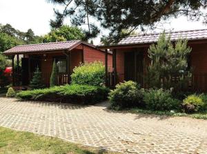 a small house with a brick walkway in front of it at Domki Przy Lesie in Stegna